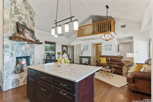 kitchen featuring a fireplace, dark brown cabinets, a kitchen island, decorative light fixtures, and dark hardwood / wood-style flooring