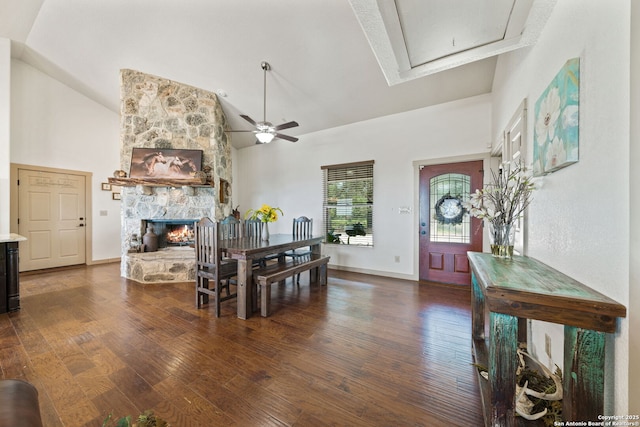 dining area featuring high vaulted ceiling, ceiling fan, dark hardwood / wood-style floors, and a stone fireplace