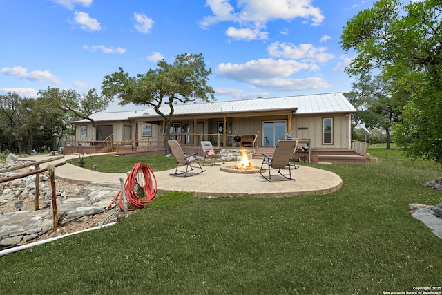 rear view of house featuring a fire pit, a yard, and a patio