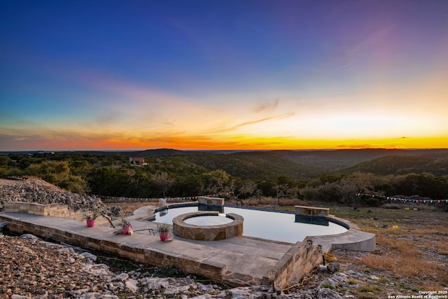 pool at dusk with a mountain view and a patio area