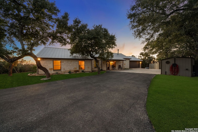 view of front of house with a garage, a yard, and a storage unit