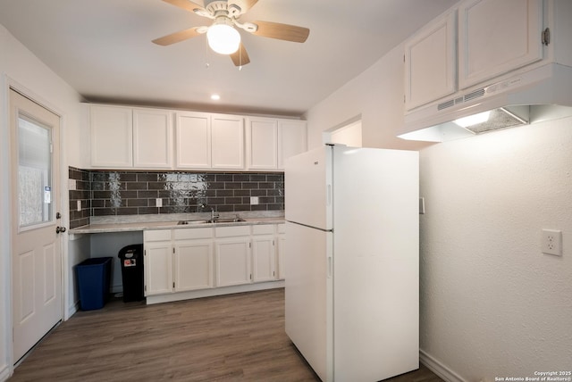 kitchen with sink, backsplash, white cabinetry, and white refrigerator