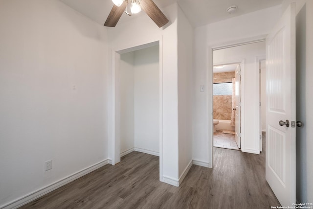 unfurnished bedroom with ceiling fan, dark wood-type flooring, and ensuite bathroom