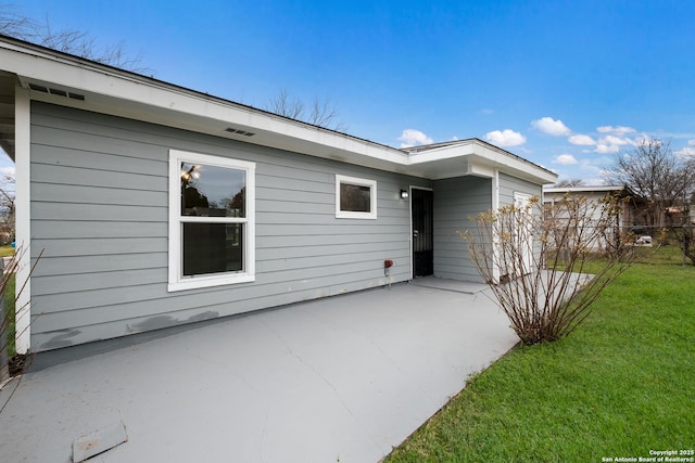 back of house with a patio area and a lawn