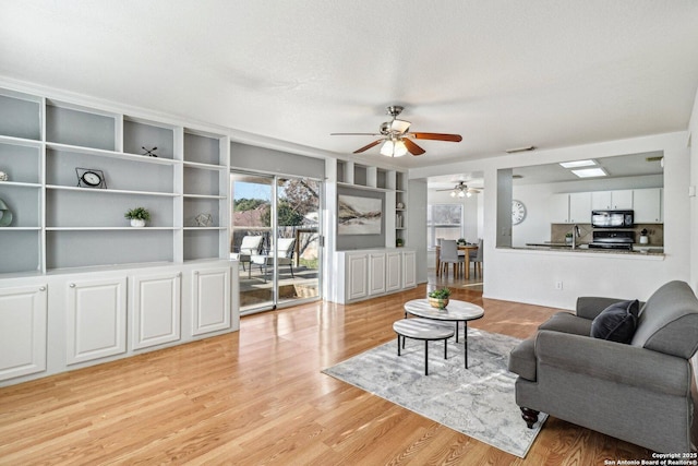 living room featuring light hardwood / wood-style floors, sink, a textured ceiling, and built in features