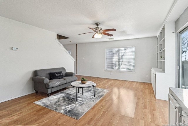 living room with built in shelves, a healthy amount of sunlight, and light wood-type flooring