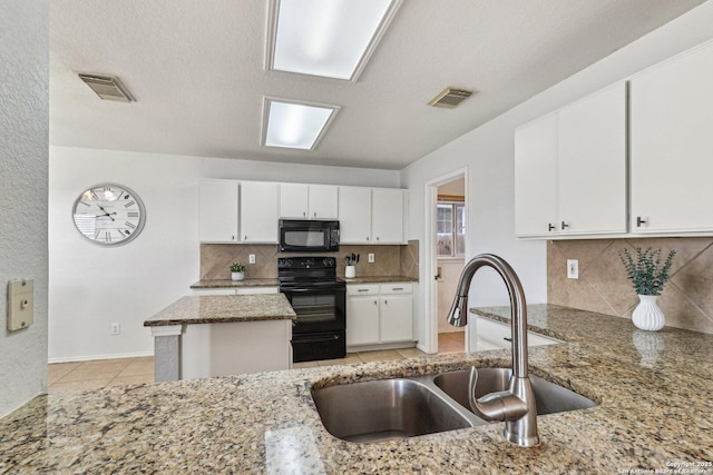 kitchen featuring black appliances, white cabinetry, light tile patterned floors, sink, and dark stone countertops