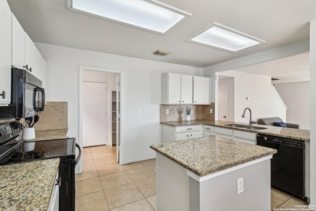 kitchen with black appliances, decorative backsplash, white cabinets, a kitchen island, and sink