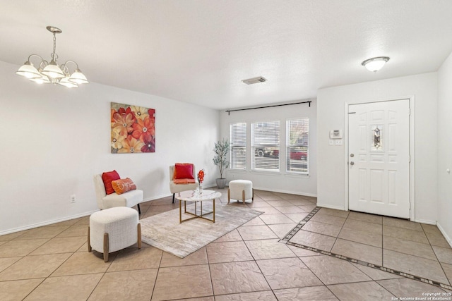 foyer with a chandelier, light tile patterned floors, and a textured ceiling