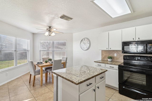 kitchen with light tile patterned floors, black appliances, tasteful backsplash, and white cabinets