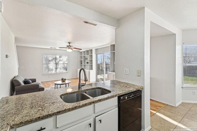 kitchen with white cabinets, built in shelves, black dishwasher, sink, and stone countertops