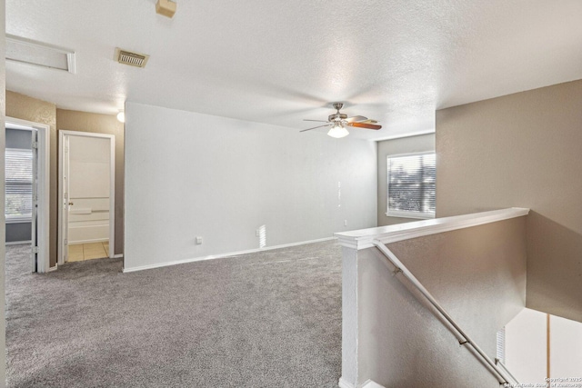 carpeted spare room featuring a textured ceiling and ceiling fan