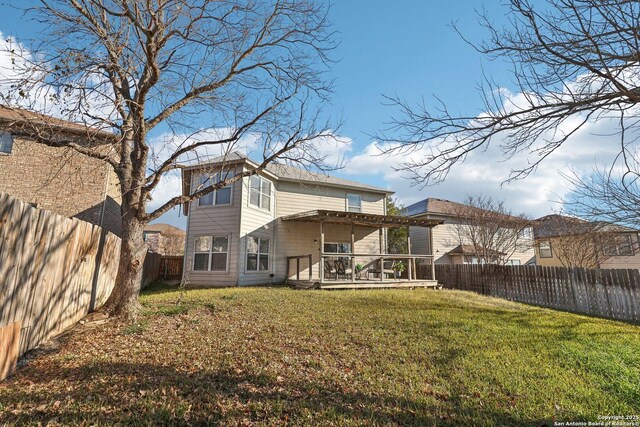 rear view of house with a wooden deck and a lawn