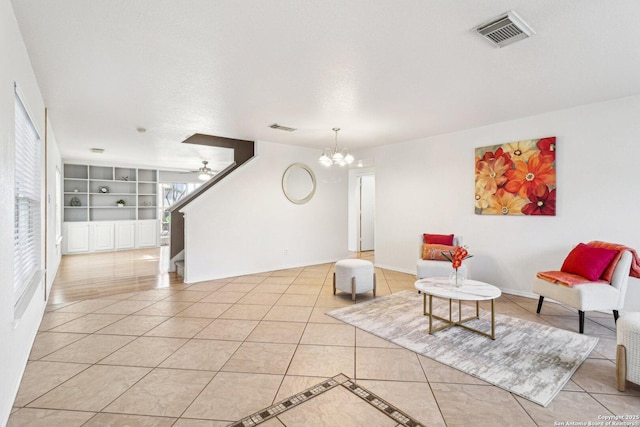 tiled living room featuring built in features, ceiling fan with notable chandelier, and a textured ceiling