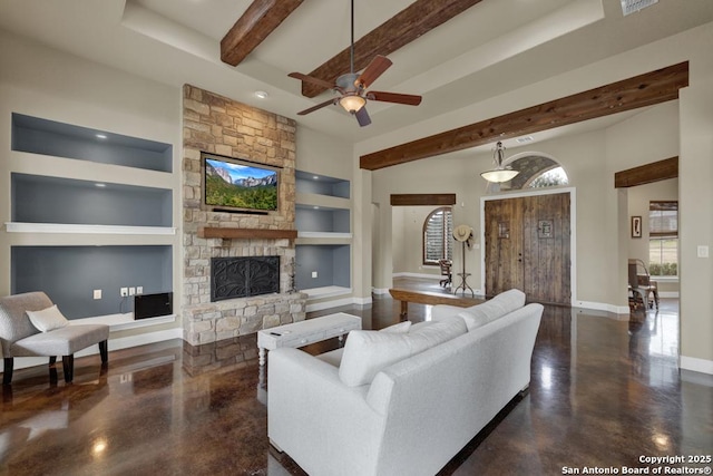 living room featuring beam ceiling, ceiling fan, a fireplace, and built in shelves