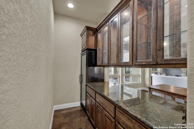 kitchen with dark stone countertops and dark brown cabinetry