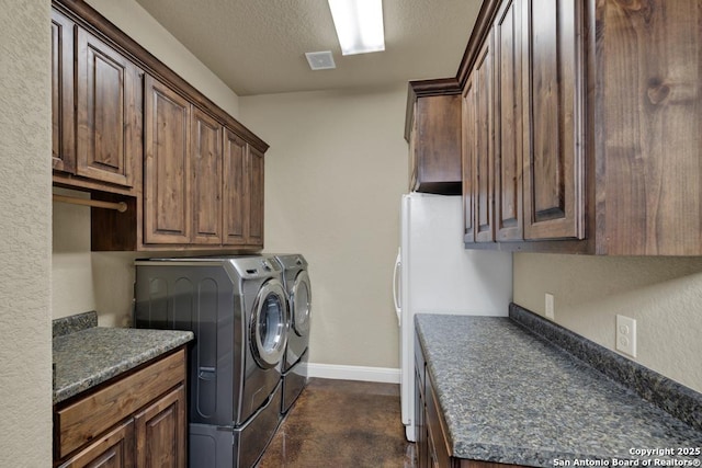 laundry area with cabinets, washing machine and clothes dryer, and a textured ceiling