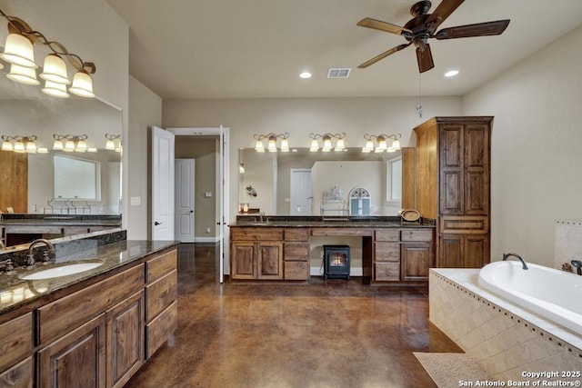 bathroom with ceiling fan, vanity, concrete flooring, and tiled tub