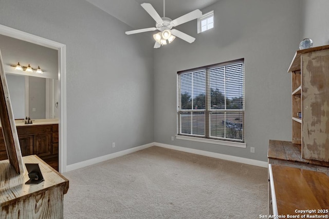 bedroom with connected bathroom, sink, light colored carpet, and a high ceiling