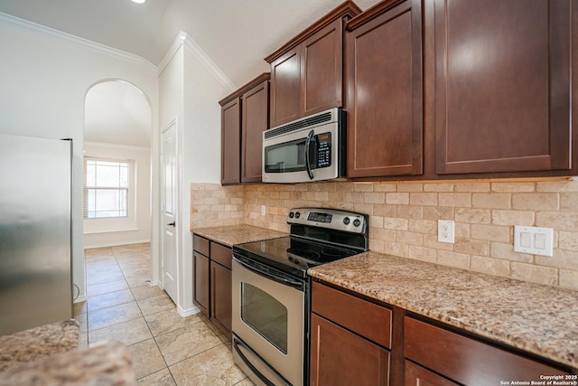 kitchen featuring crown molding, backsplash, light stone countertops, light tile patterned flooring, and stainless steel appliances