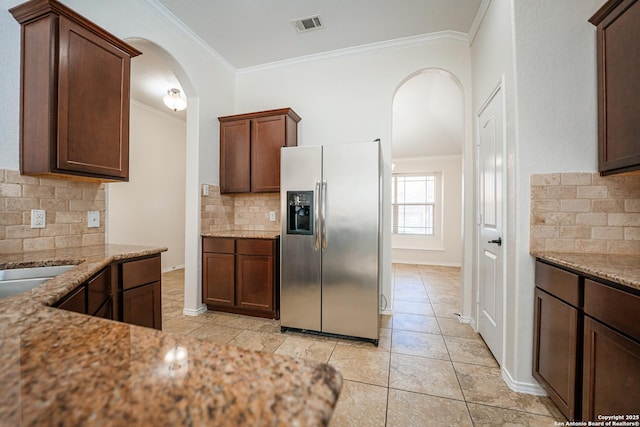 kitchen featuring stainless steel fridge with ice dispenser, light stone counters, crown molding, and tasteful backsplash