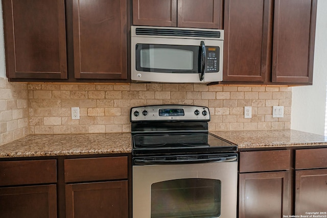 kitchen featuring light stone counters, tasteful backsplash, dark brown cabinetry, and appliances with stainless steel finishes