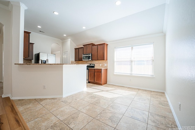 kitchen with light stone countertops, appliances with stainless steel finishes, kitchen peninsula, ornamental molding, and backsplash