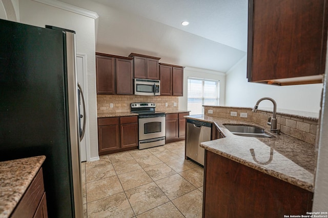 kitchen featuring appliances with stainless steel finishes, sink, vaulted ceiling, light stone counters, and light tile patterned floors