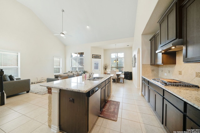 kitchen featuring an island with sink, dark brown cabinetry, light stone countertops, and appliances with stainless steel finishes