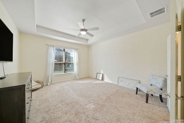 interior space with ceiling fan, light colored carpet, and a raised ceiling