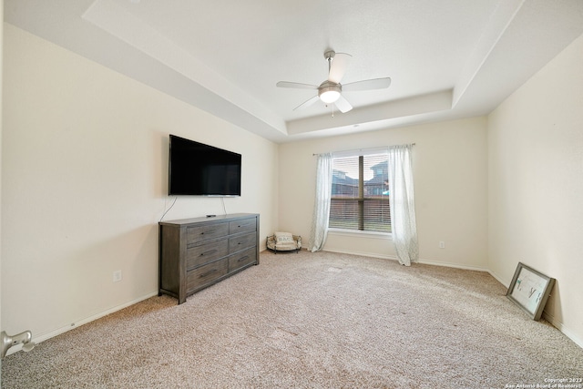 unfurnished bedroom with light colored carpet, ceiling fan, and a raised ceiling