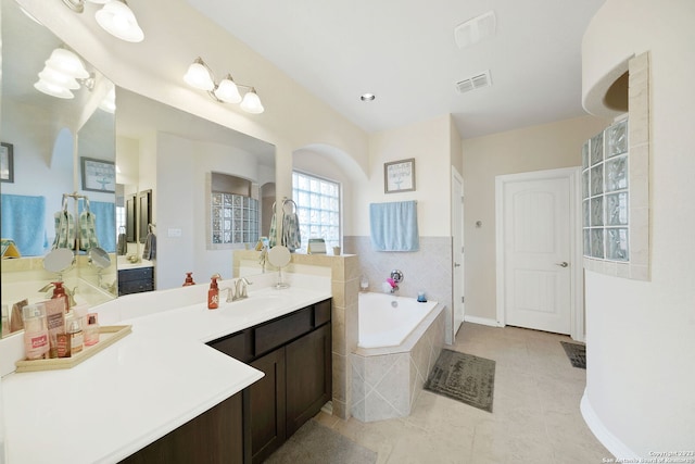 bathroom with tiled bath, tile patterned floors, and vanity