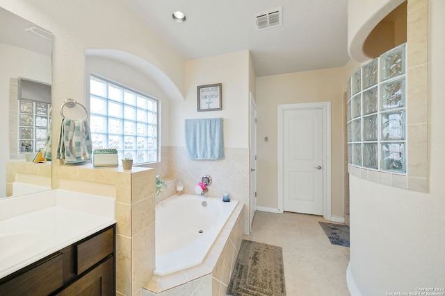 bathroom featuring vanity, a relaxing tiled tub, and tile patterned flooring