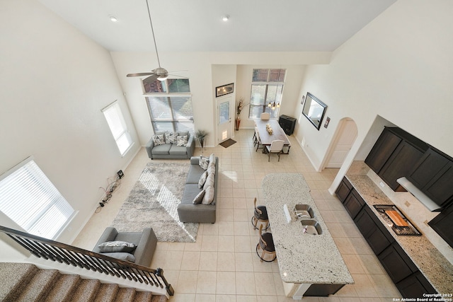 living room with sink, a high ceiling, light tile patterned floors, and ceiling fan