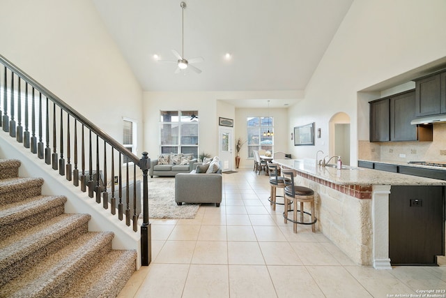 tiled living room with sink, ceiling fan, and high vaulted ceiling