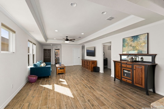 living room with crown molding, ceiling fan, and a tray ceiling