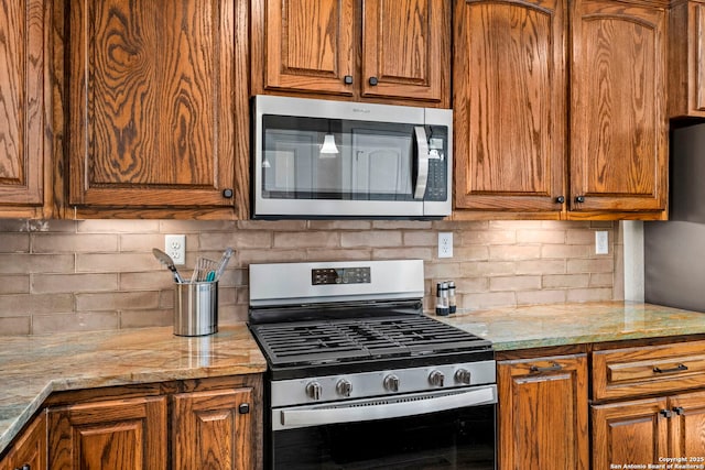 kitchen with light stone countertops, backsplash, and stainless steel appliances