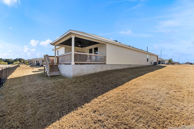 rear view of property featuring a yard, ceiling fan, and central air condition unit