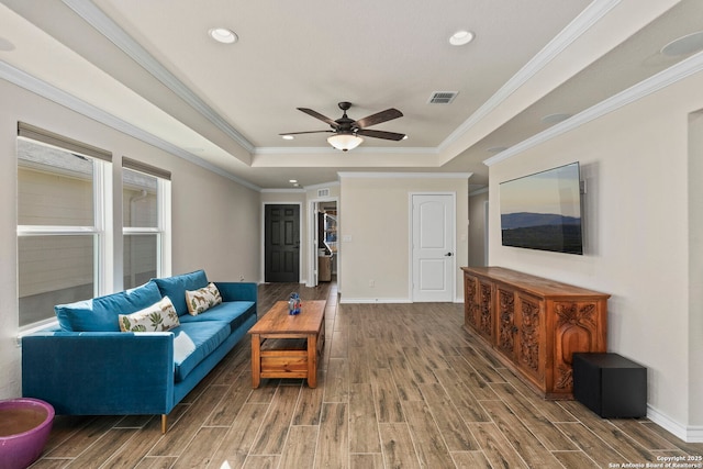 living room with crown molding, ceiling fan, and a tray ceiling