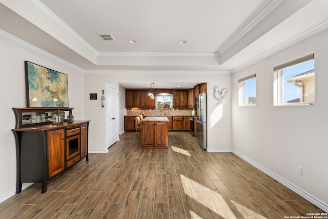 kitchen with stainless steel refrigerator, dark hardwood / wood-style floors, a raised ceiling, and hanging light fixtures