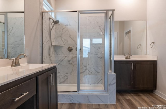 bathroom with wood-type flooring, a shower with door, and vanity