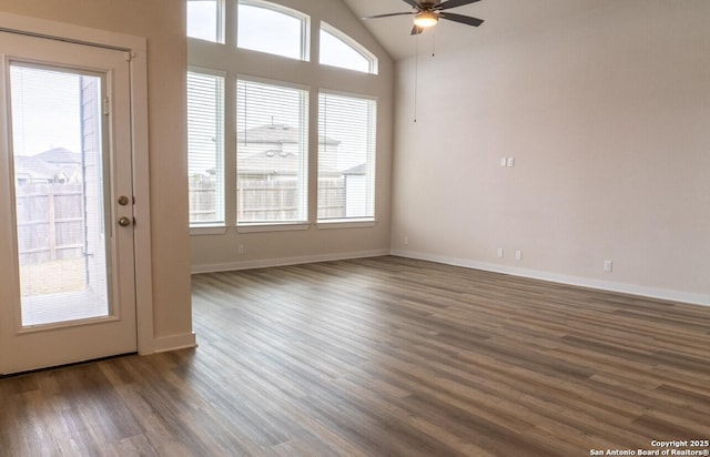 empty room with ceiling fan, plenty of natural light, dark hardwood / wood-style floors, and vaulted ceiling