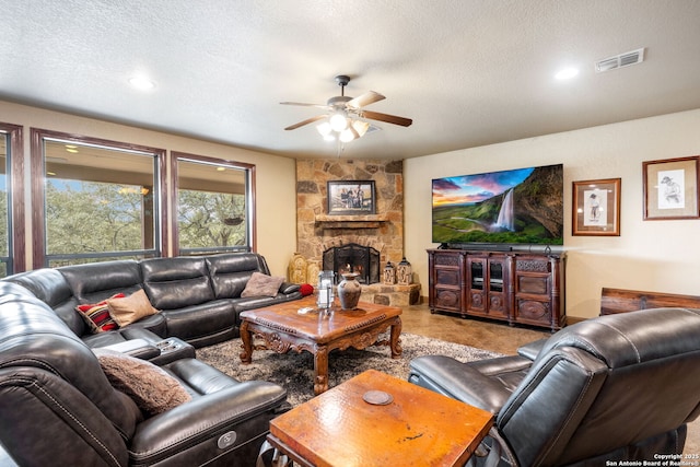 living room featuring ceiling fan, a fireplace, and a textured ceiling