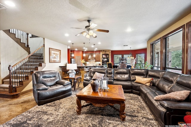 living room featuring ceiling fan and a textured ceiling