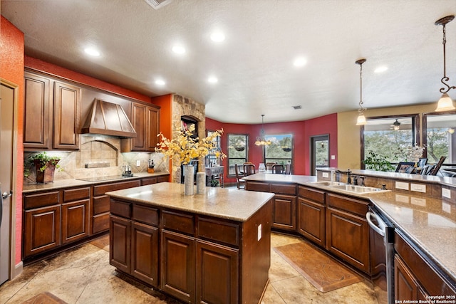 kitchen featuring dishwasher, custom range hood, hanging light fixtures, sink, and a kitchen island