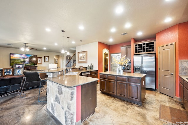 kitchen with appliances with stainless steel finishes, decorative light fixtures, sink, a large island, and a breakfast bar area