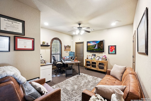 home office featuring ceiling fan, dark carpet, and a textured ceiling