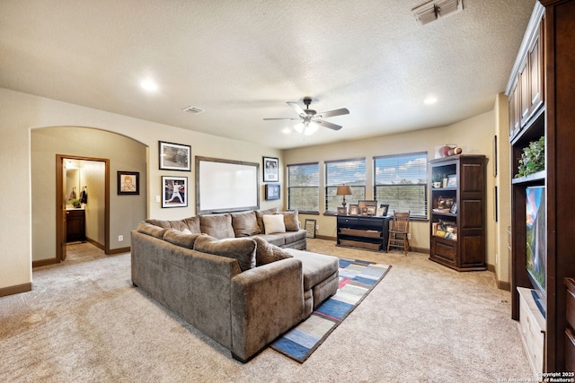 living room with ceiling fan, a textured ceiling, and light carpet