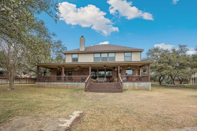 back of house with ceiling fan and a yard