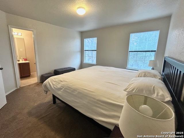 carpeted bedroom with a textured ceiling and ensuite bathroom